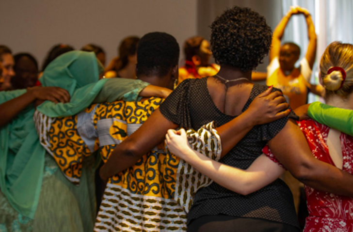 Photo of women with linked arms in a circle from the WPS Nairobi workshop