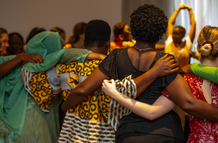 Group of women linking arms in a circle at the WPS workshop in Nairobi